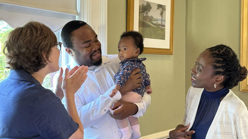photo of Dr. Avungbeto holding his baby, flanked by Dr. McGowan and Dr. Avungbeto's wife